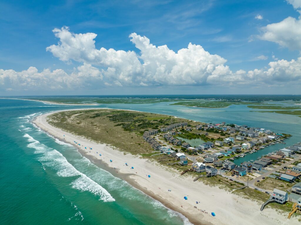 Aerial view of Serenity Point shoreline and surrounding water under bright summer clouds