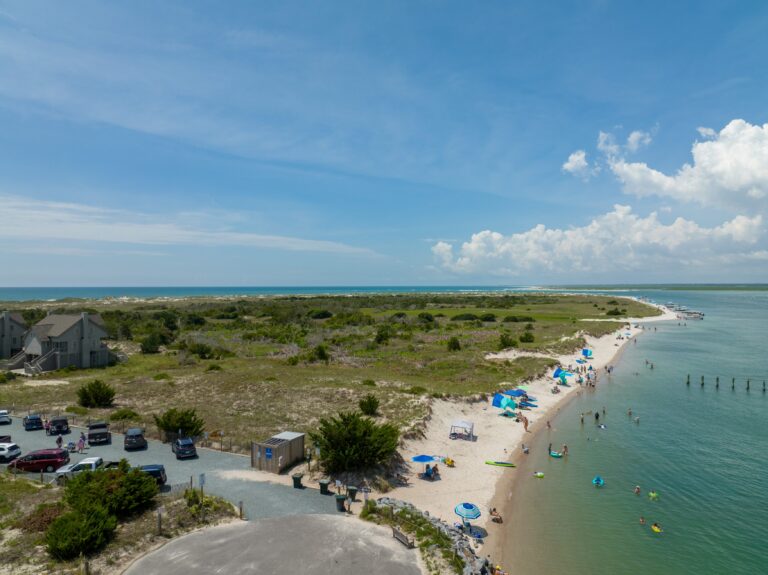 Aerial view looking along the beach curve at Serenity Point with dunes and clear water