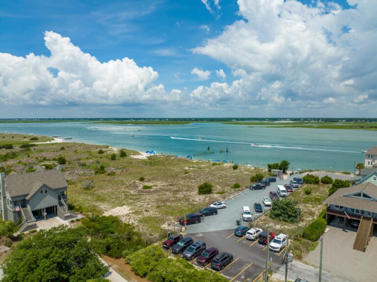 Aerial view of Serenity Point with inlet water, nearby homes, dunes, and beach access