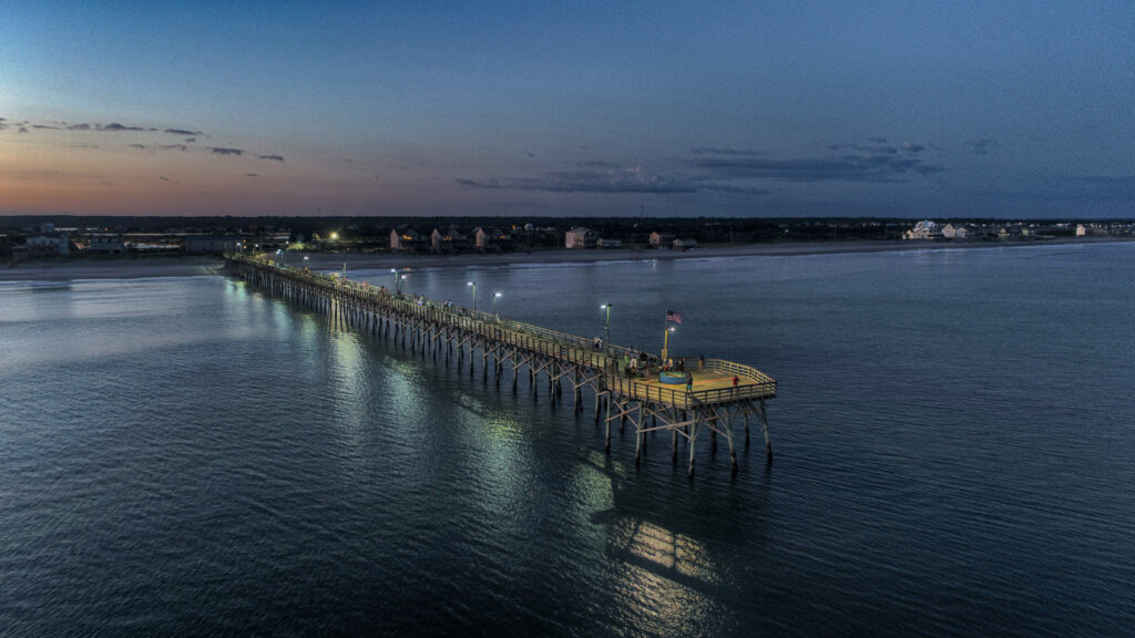 Seaview Fishing Pier at dusk — Photo by Buddy Seaview Fishing Pier in North Topsail Beach at dusk, with lights reflected in the ocean. Photograph by Buddy, Baker Aerial Images.