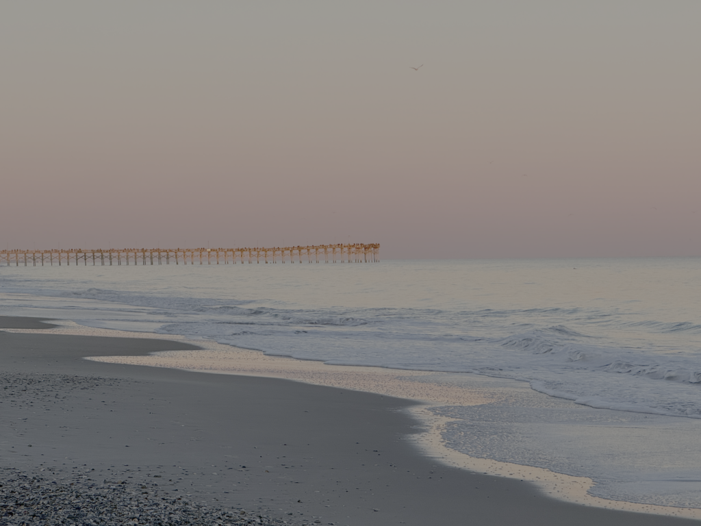 Surf City Pier — Photo by Isaac Surf City Pier beneath a soft pink evening sky, with waves washing along the beach. Photograph by Isaac.