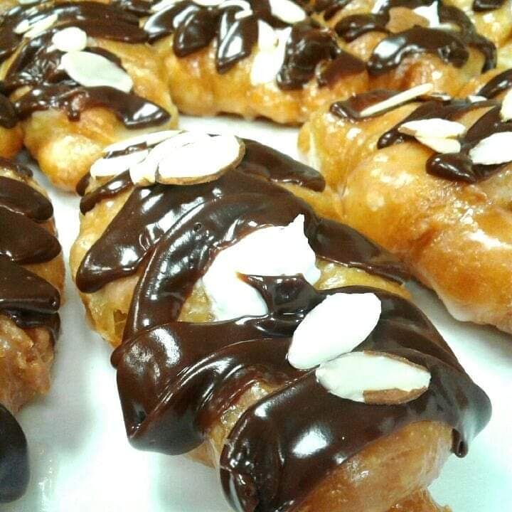 Glazed croissants drizzled with chocolate and icing and topped with sliced almonds