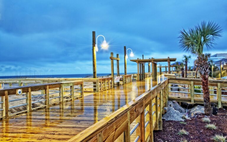 The Carolina Beach boardwalk at dusk with lamps and the ocean