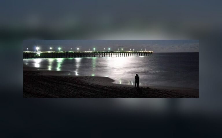 Surf City Ocean Pier lit at night over the water