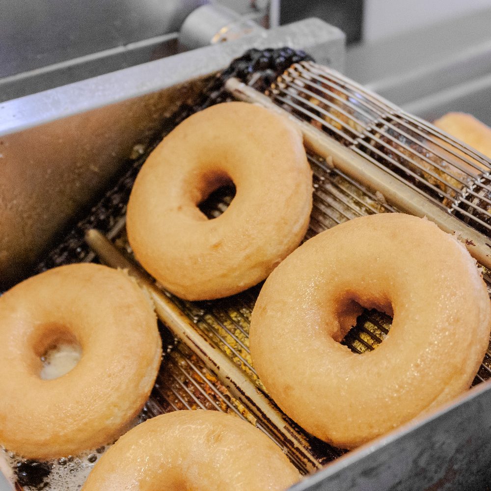 Cake donuts frying golden in a basket at Daybreak Donuts