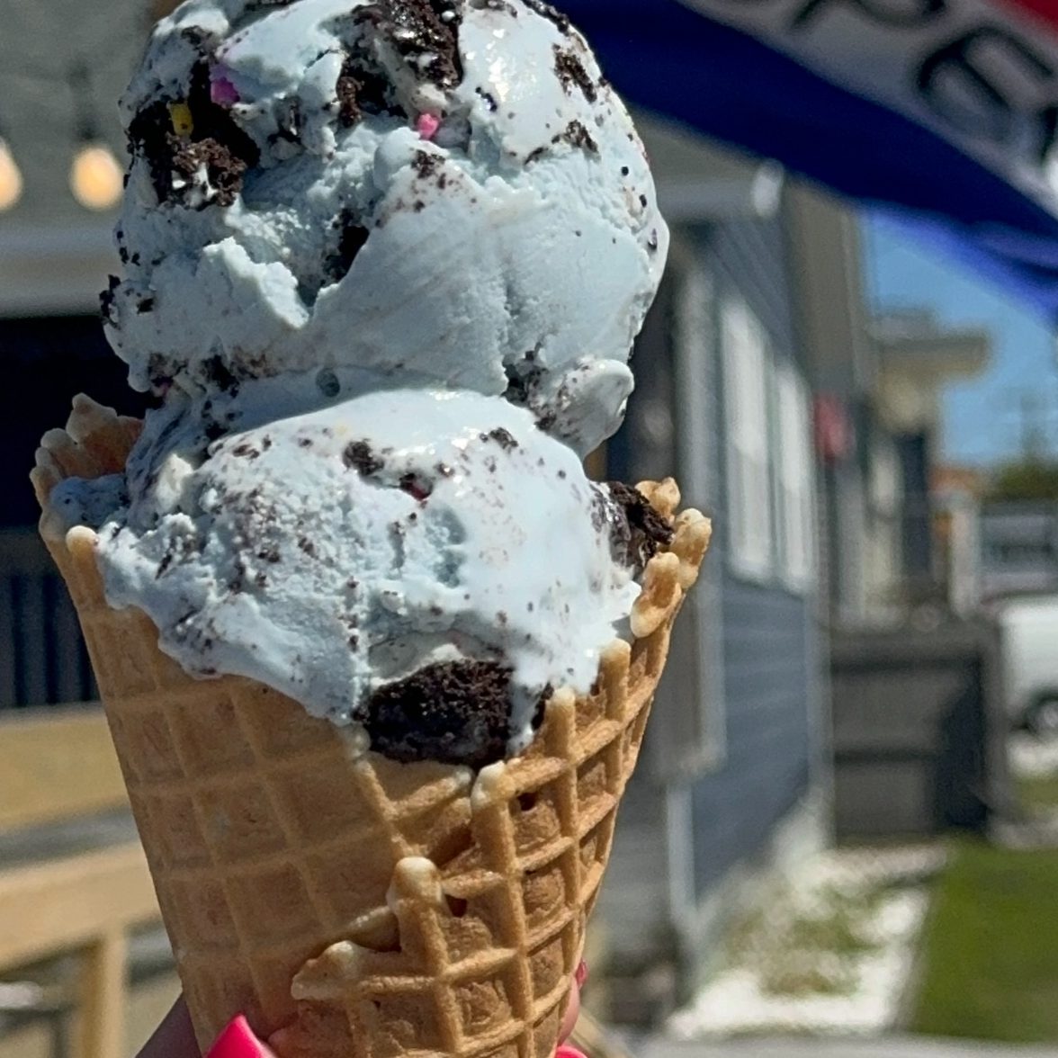 Two scoops of blue cookie ice cream in a waffle cone