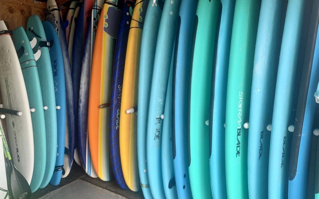 A rack of rental soft-top surfboards