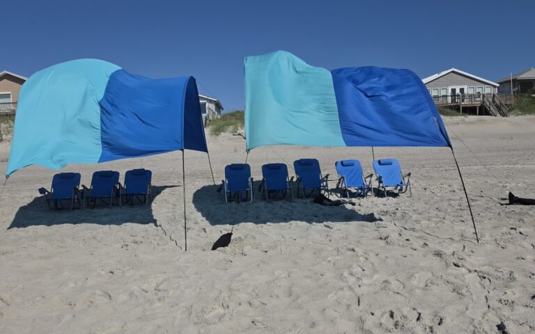 Two wind shades over rows of blue beach chairs