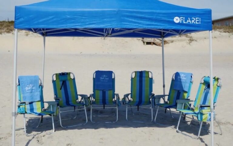A blue canopy over six striped beach chairs