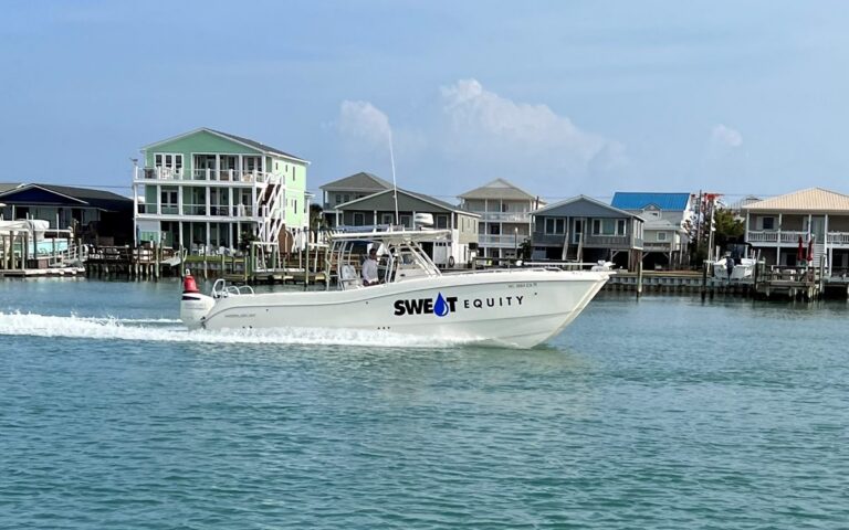 The catamaran Sweat Equity running past Topsail homes