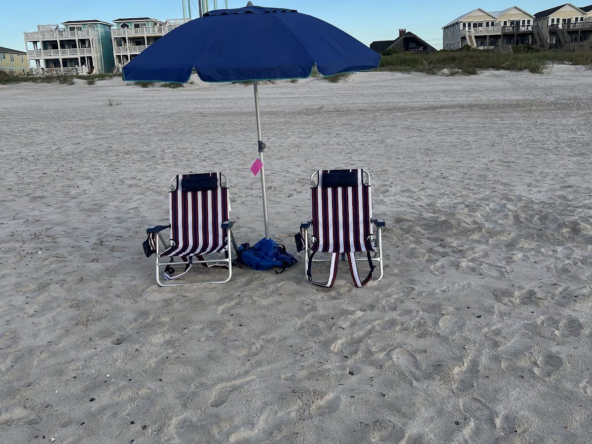 Two beach chairs under an umbrella