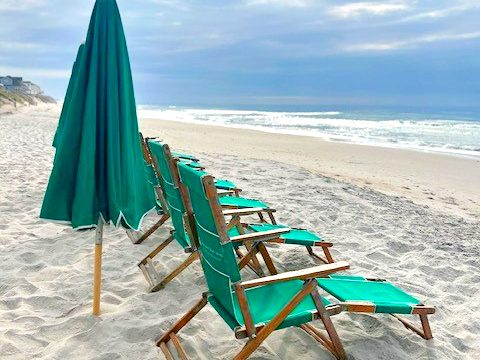 Green beach chairs and a closed umbrella on the sand