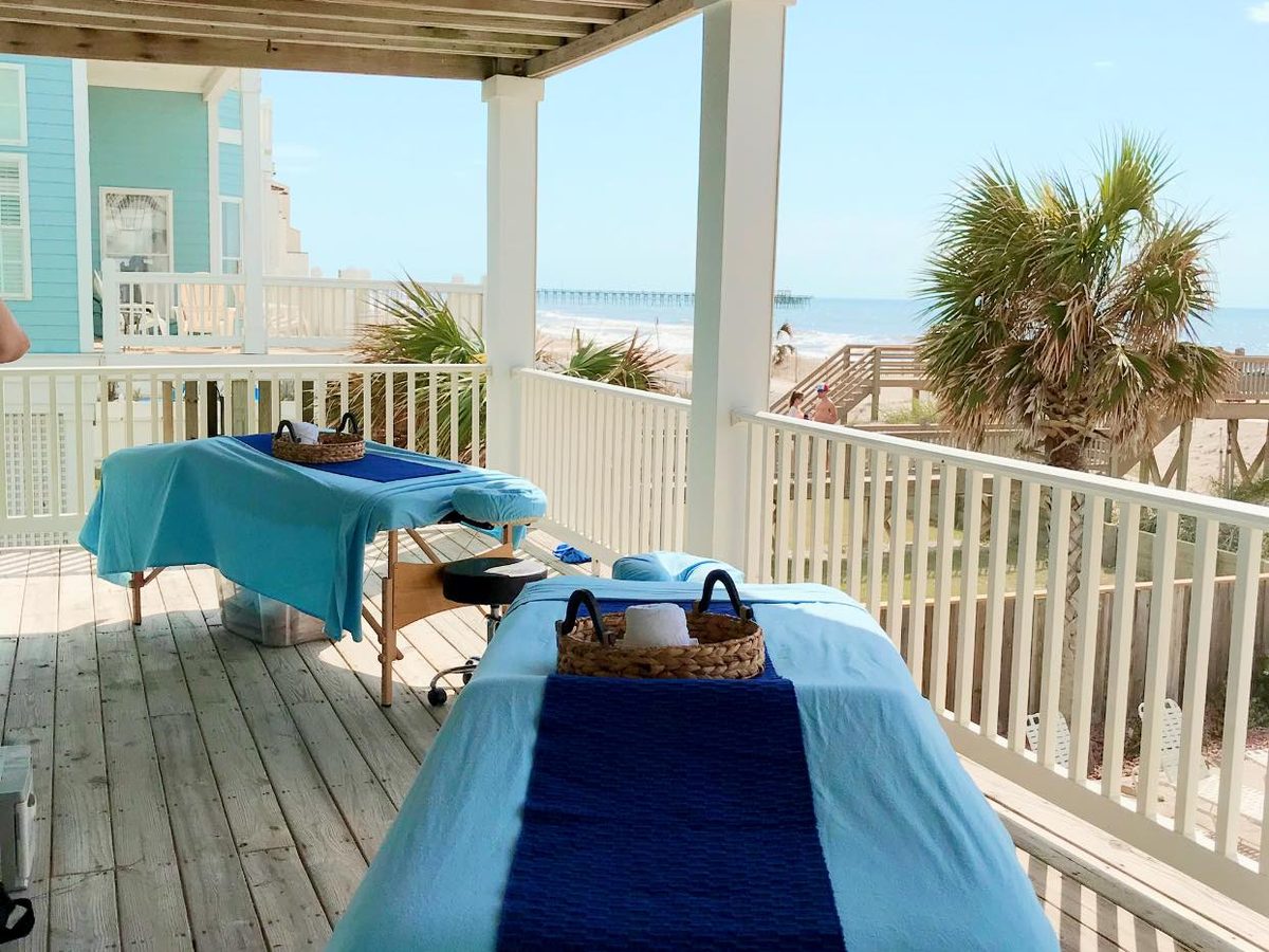 Two massage tables on a beach-house deck