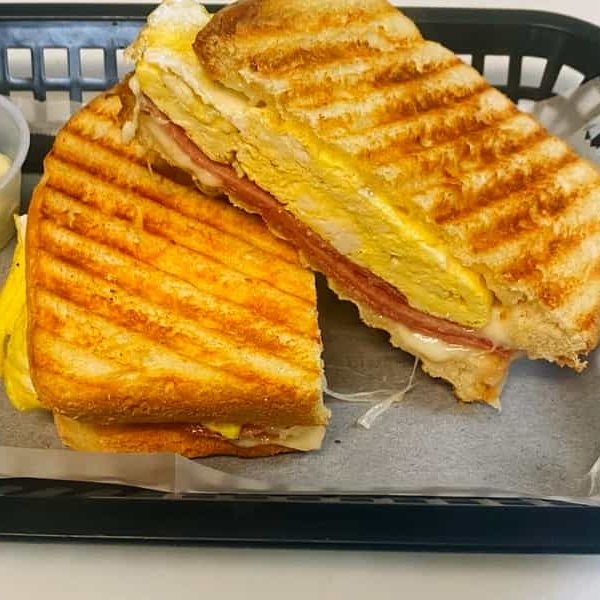 A pressed breakfast panini with egg, meat and cheese, cut in half