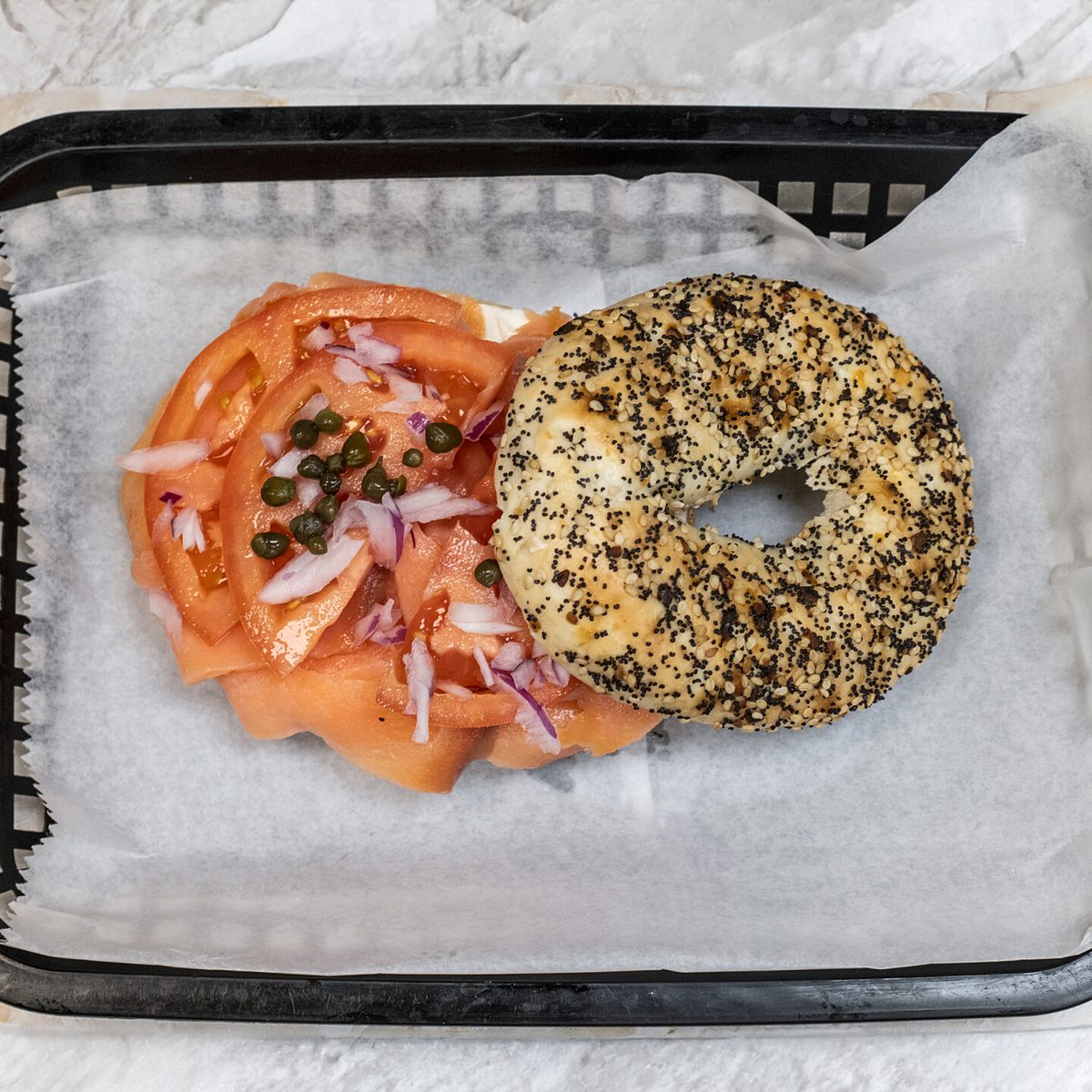 An everything bagel with smoked salmon, tomato, red onion and capers