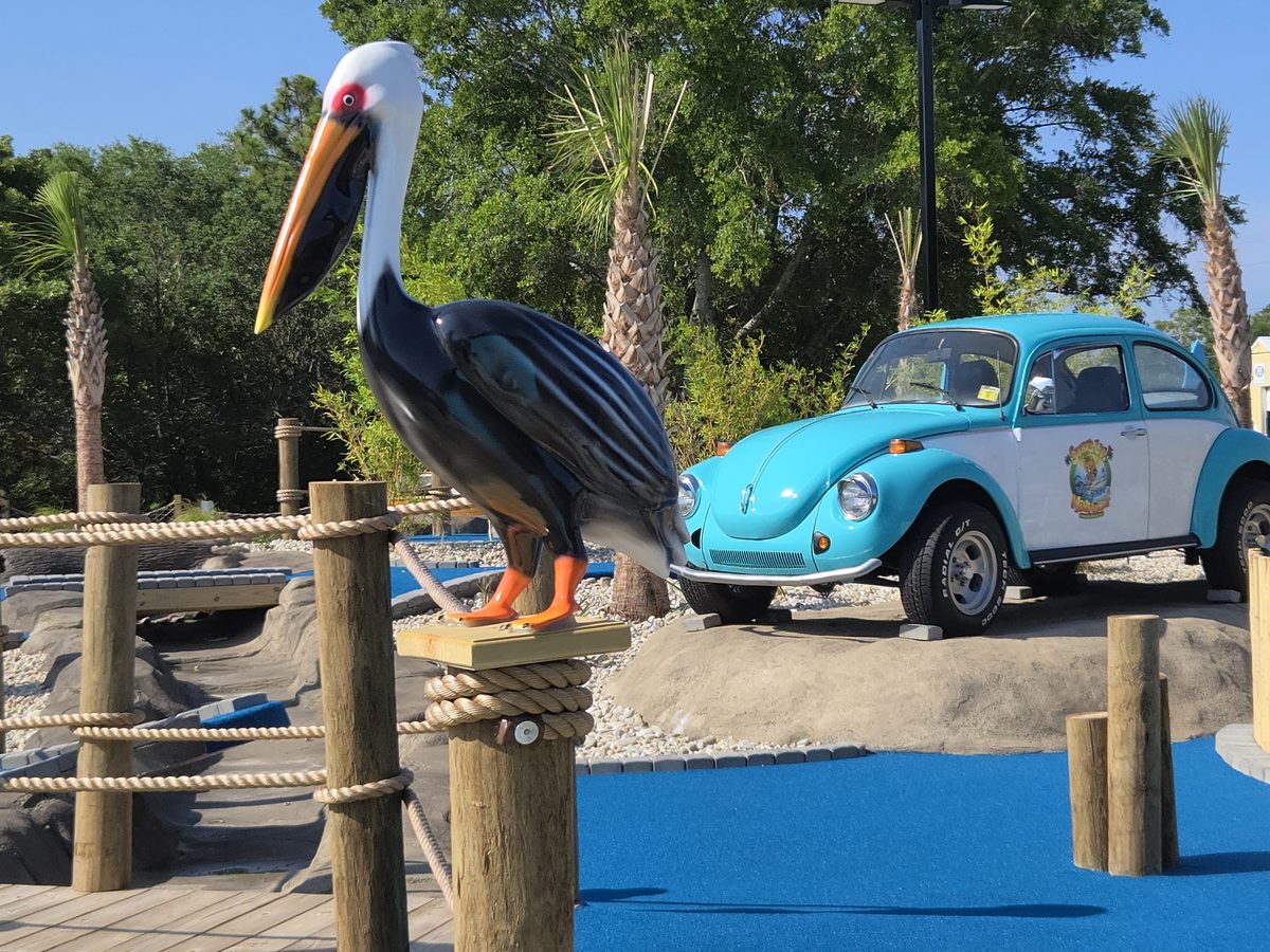 A pelican statue and the vintage VW Bug on the course